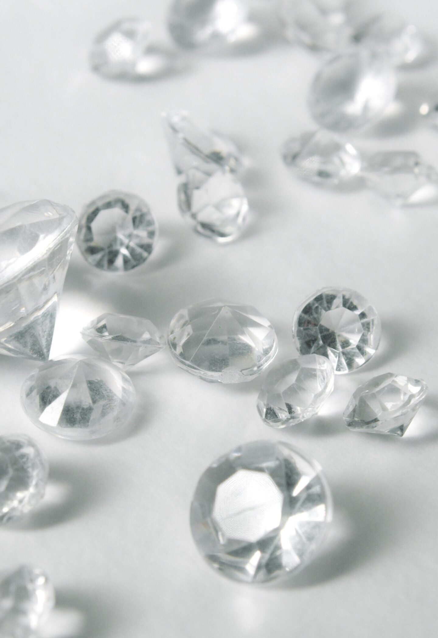 A close-up of various clear-cut gemstones on a white surface, showcasing their sparkle and clarity.